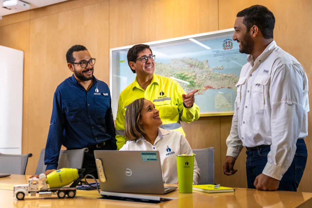 Cuatro personas del equipo de Argos trabajan en una oficina frente a un mapa de República Dominicana