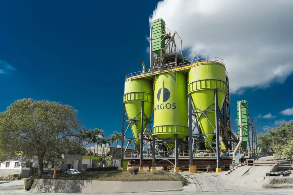 Silos verdes de la planta de Argos en República Dominicana bajo un cielo despejado